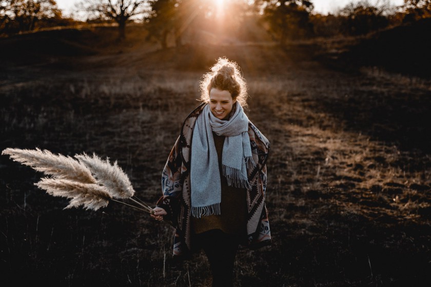 Frau während eines Sonnenuntergangs mit Pampasgras