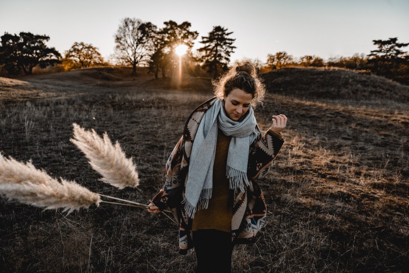 Frau während eines Sonnenuntergangs mit Pampasgras