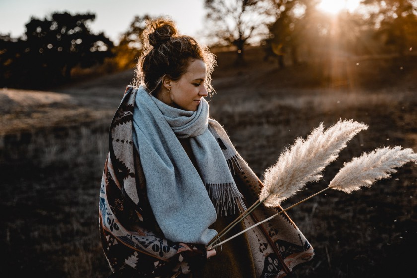 Frau während eines Sonnenuntergangs mit Pampasgras