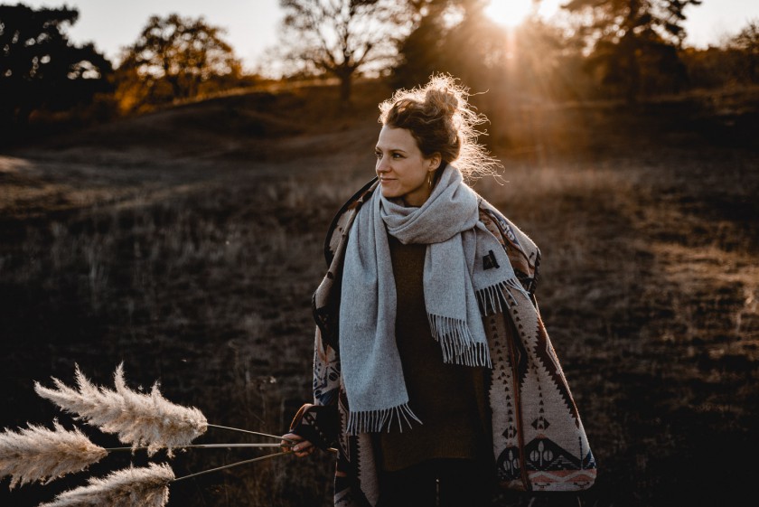 Frau während eines Sonnenuntergangs mit Pampasgras